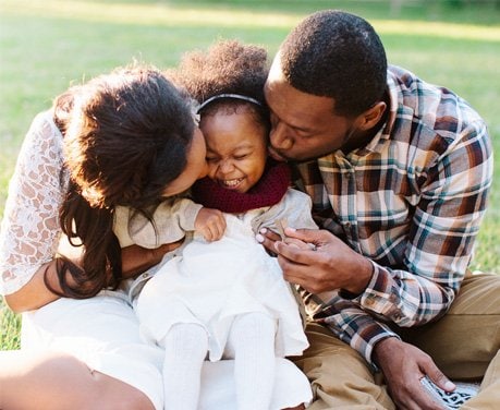 mother and father kiss young daughter