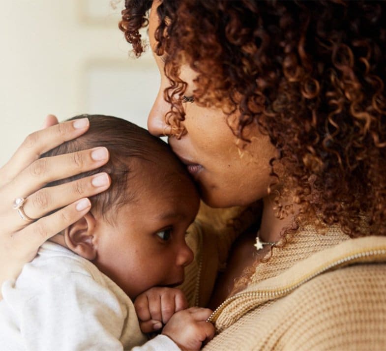mother kisses newborn baby's head
